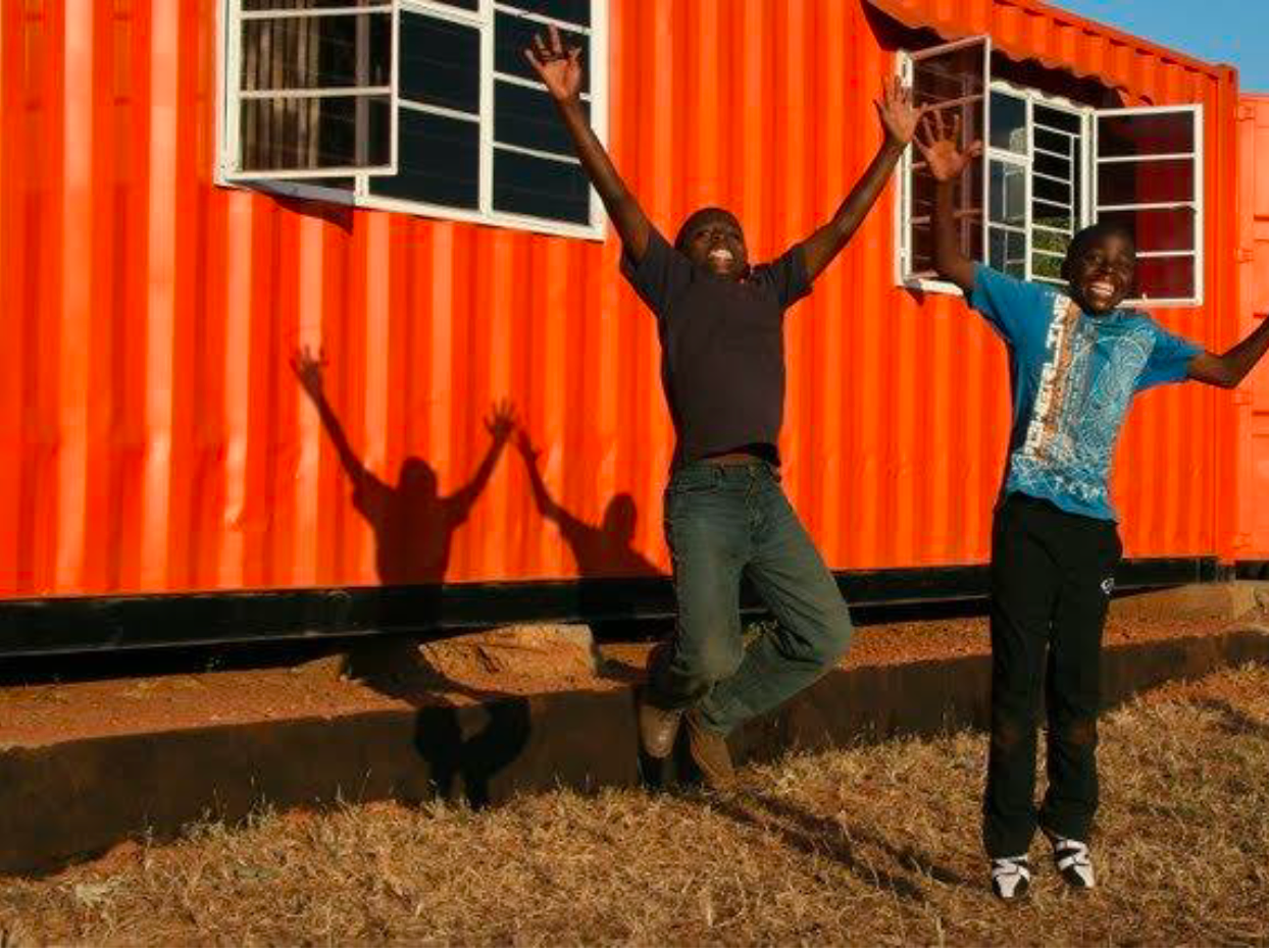 Two boys jumping next to a portable building